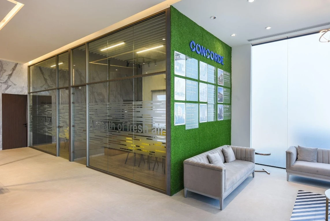 Waiting area beside a glazed meeting room and green feature wall, commercial interior design in Raipur