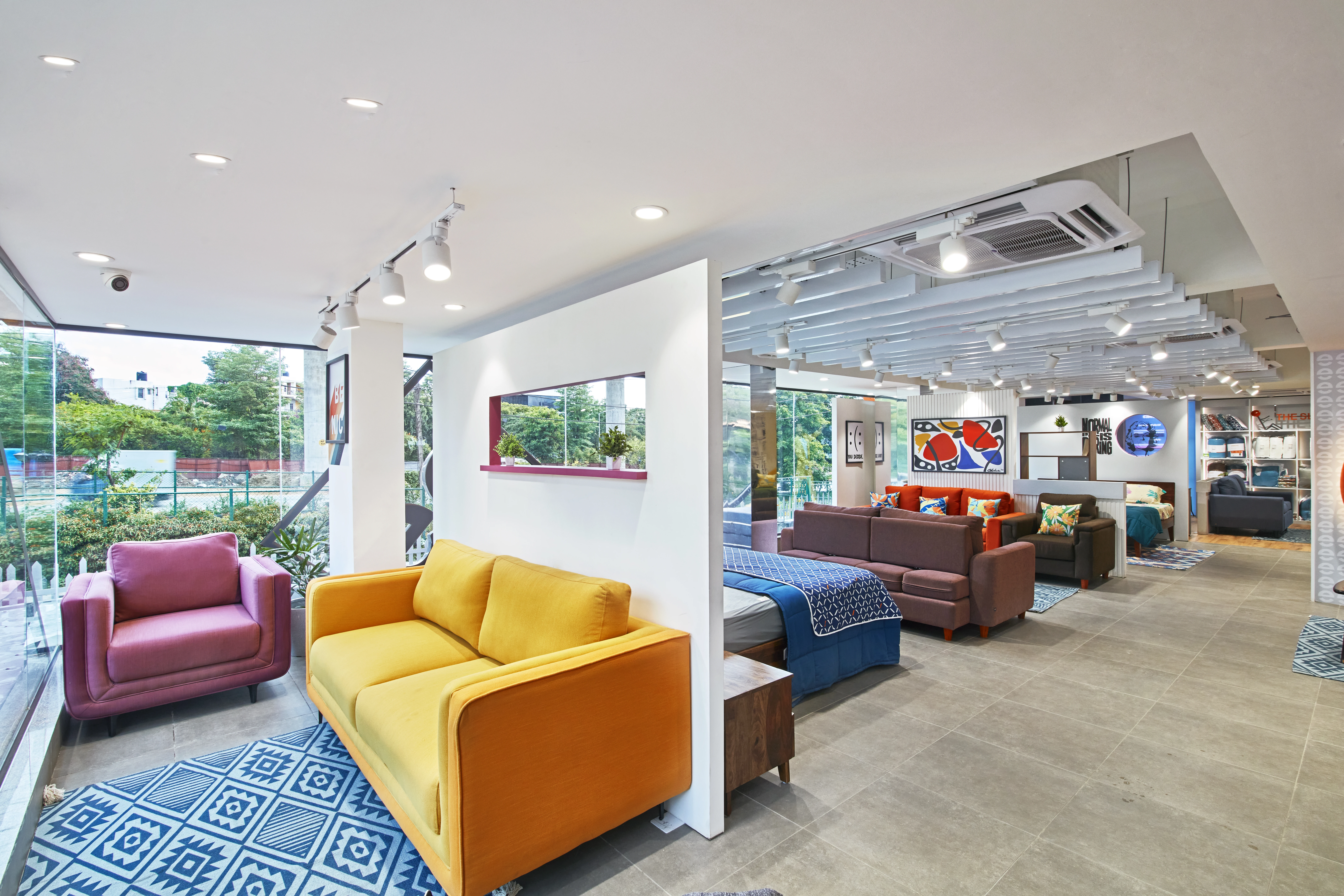 Furniture showroom with yellow and burgundy sofas, Sleepy Head retail interior design project in Bangalore by Mustardd Spaces
