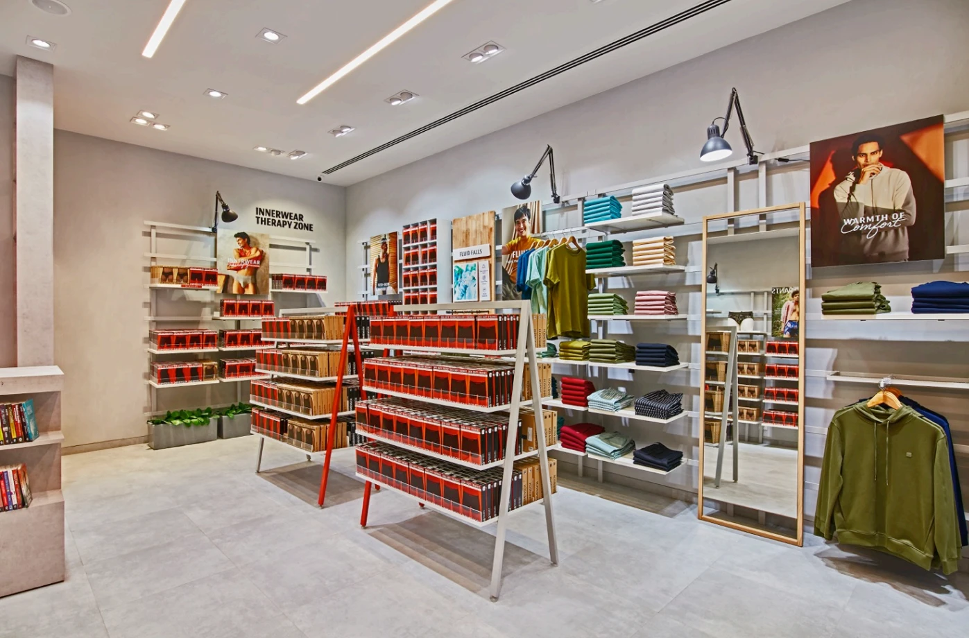 Clothing store with orange shelving and freestanding display racks, DaMensch retail interior design project in Bangalore by Mustardd Spaces